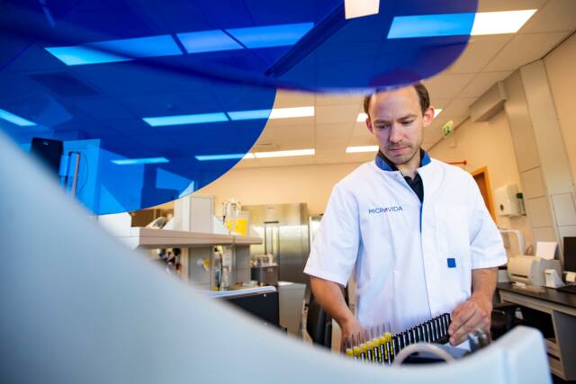 man draagt een slede met onderzoeksmateriaal in het lab