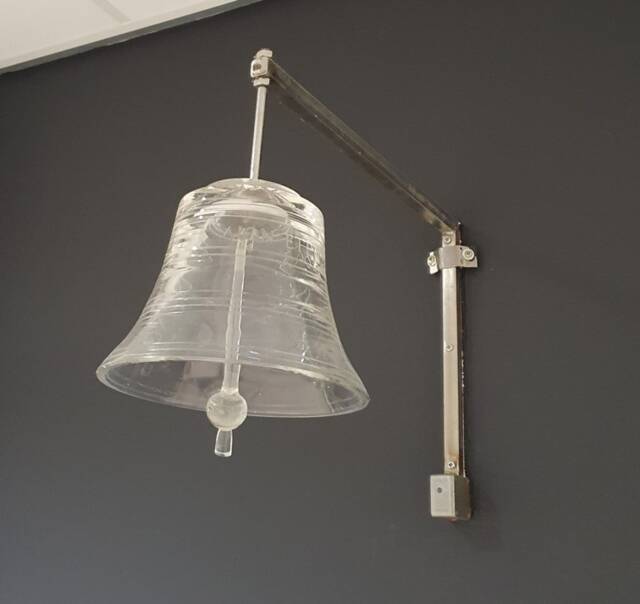 Glazen klok/bel hangt aan een donkergrijze muur